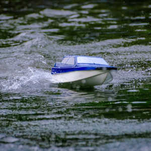 A photograph of a radio-controlled model boat on the lake.