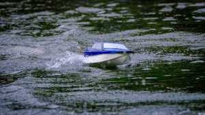 A photograph of a radio-controlled model boat on the lake.