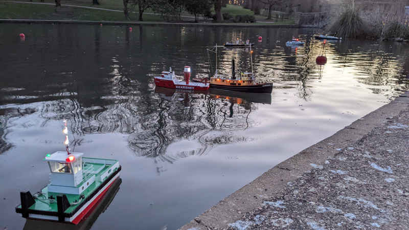 A photo of some model boats sailing on the lake. 